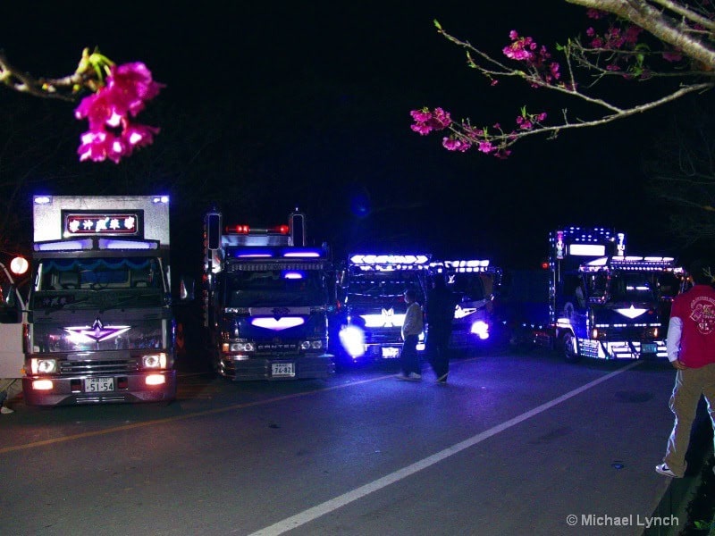 Decorated trucks illuminate the Cherry Blossoms at night