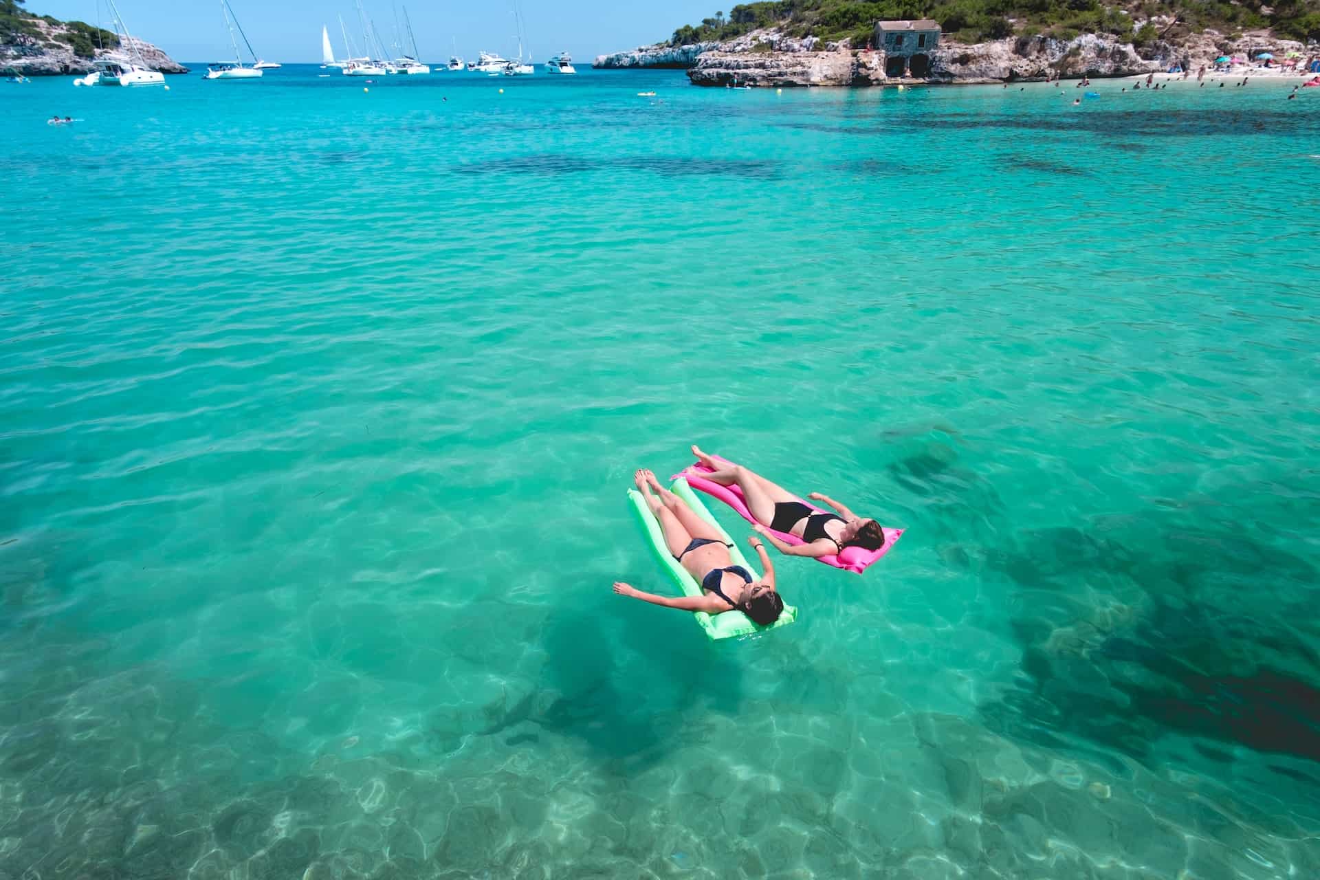 Women floating on the water while traveling in Mallorca, Spain (photo: Jo Kassis).