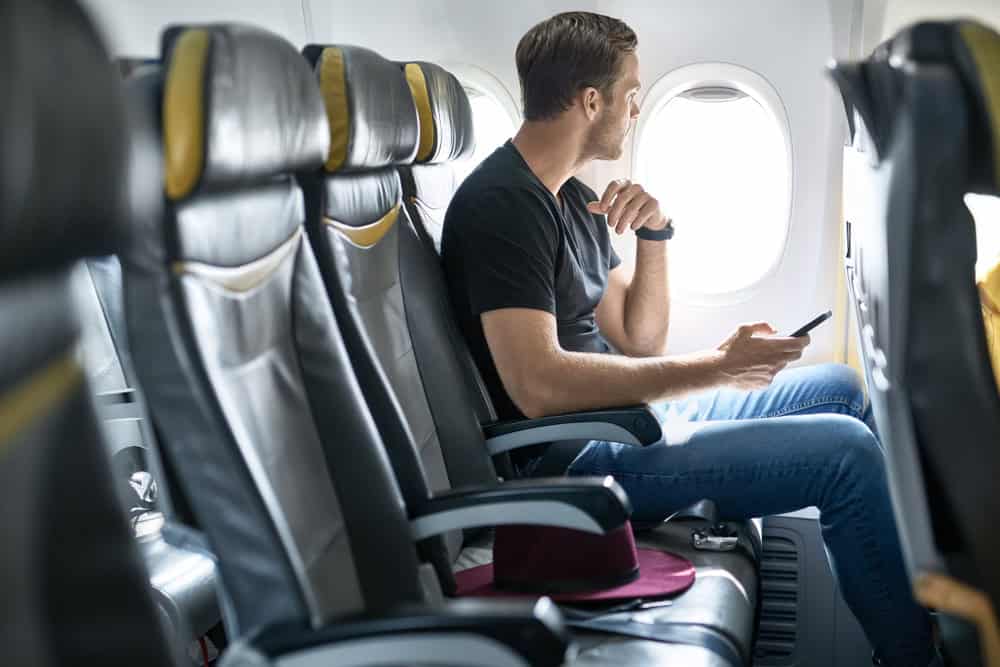 Man with smartphone on a long haul flight