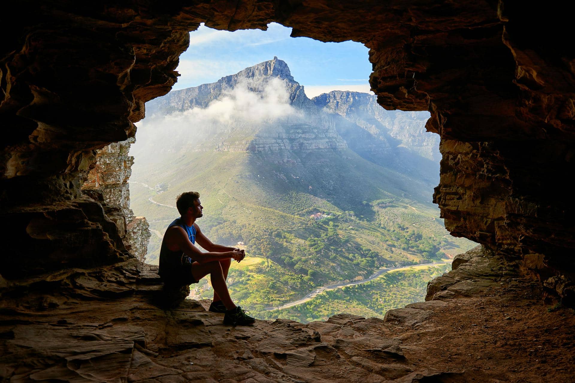 A man enjoying the mountain view from a cave (photo: M Venter).