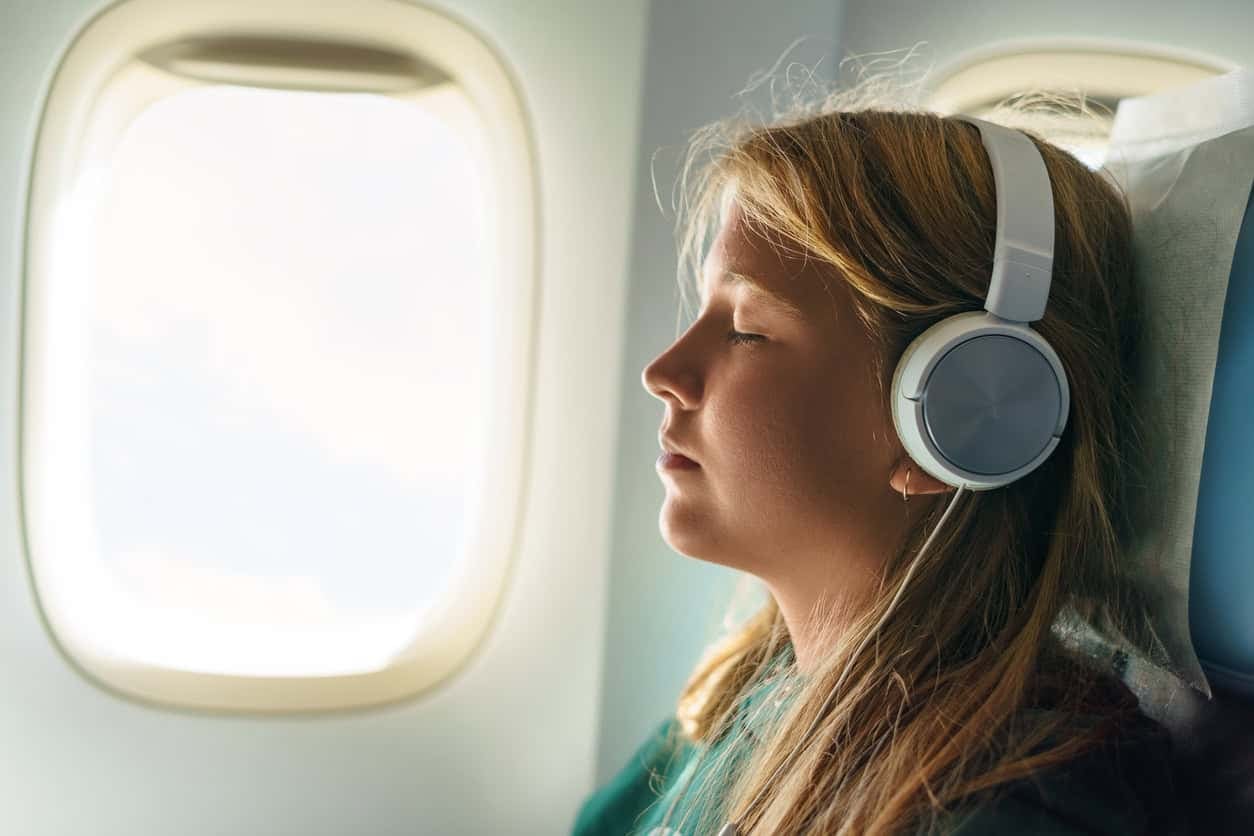 Woman with headphones listening to a travel audiobook on a flight  (photo: Eugen Fedorov).