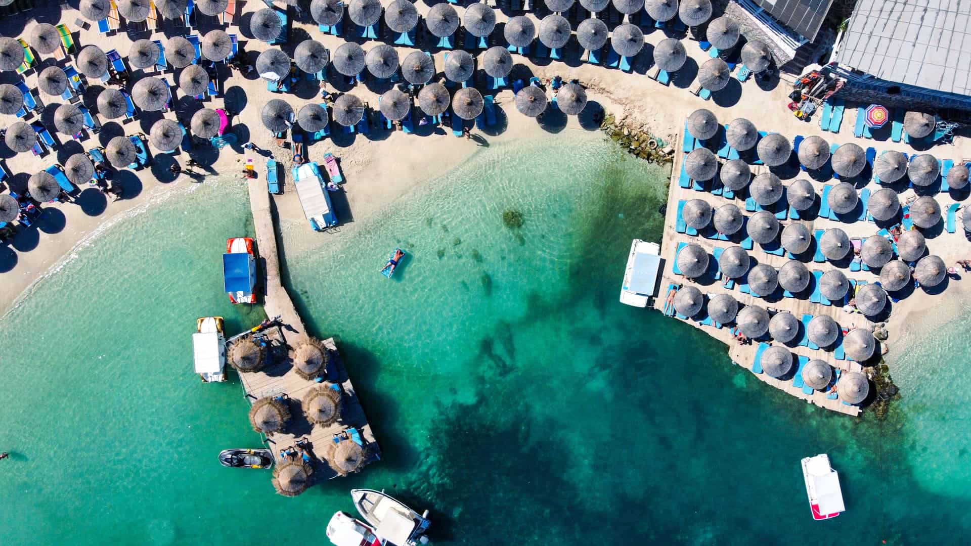 Bathers and umbrellas in Ksamil, a beach destination in Albania (photo: B, Unsplash).