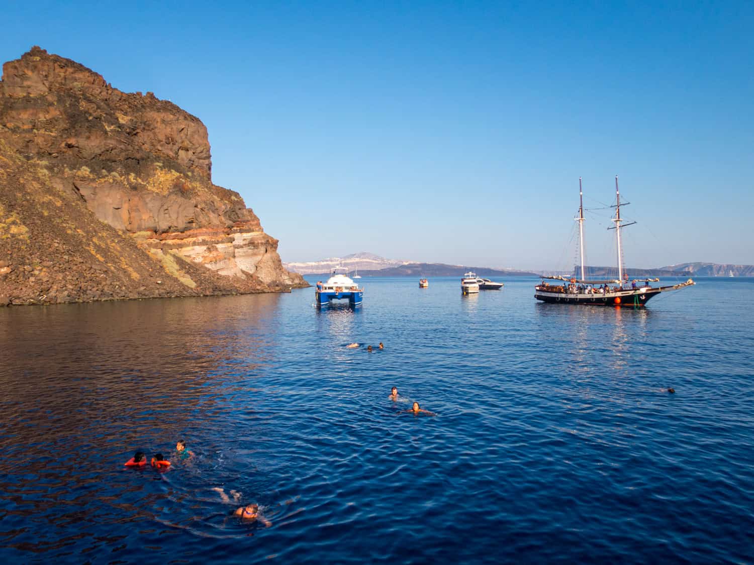 Boats and tourists swimming off Therasia Island.