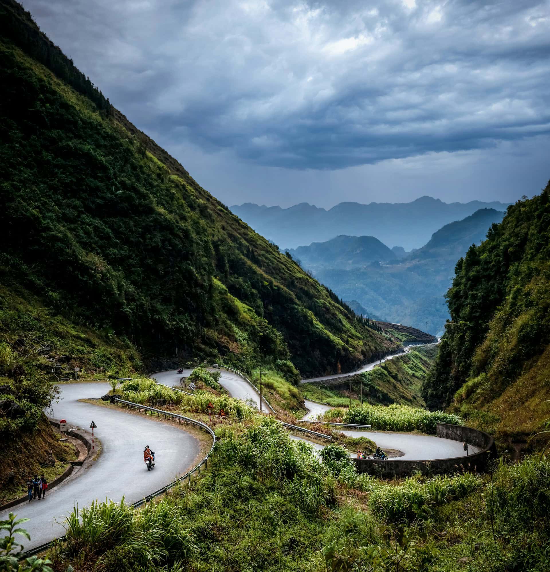 A motorbike driving on a twisting road in Ha Giang, Vietnam, a country where one's travel budget can go far (photo: Huy Nguyen, Unsplash).