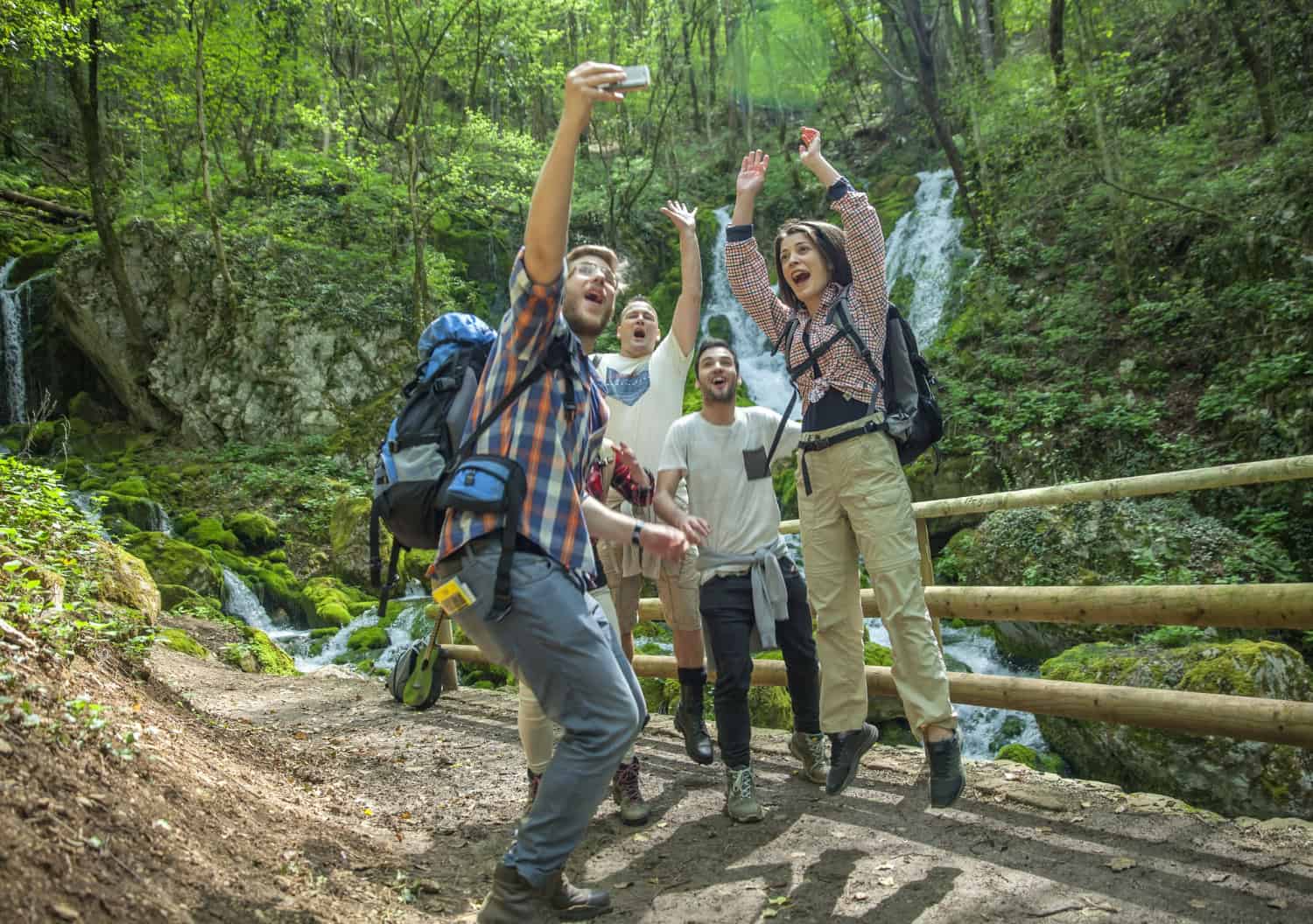 Friends taking selfie by waterfall while hiking (photo by wirestock on Freepik).