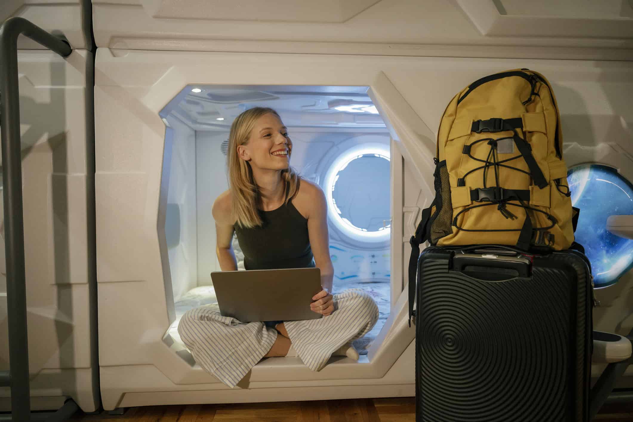 Young woman using Wi-Fi at a capsule hotel is convenient, but it's also one of the biggest digital security risks backpackers face (photo: Franci Leoncio/iStock).