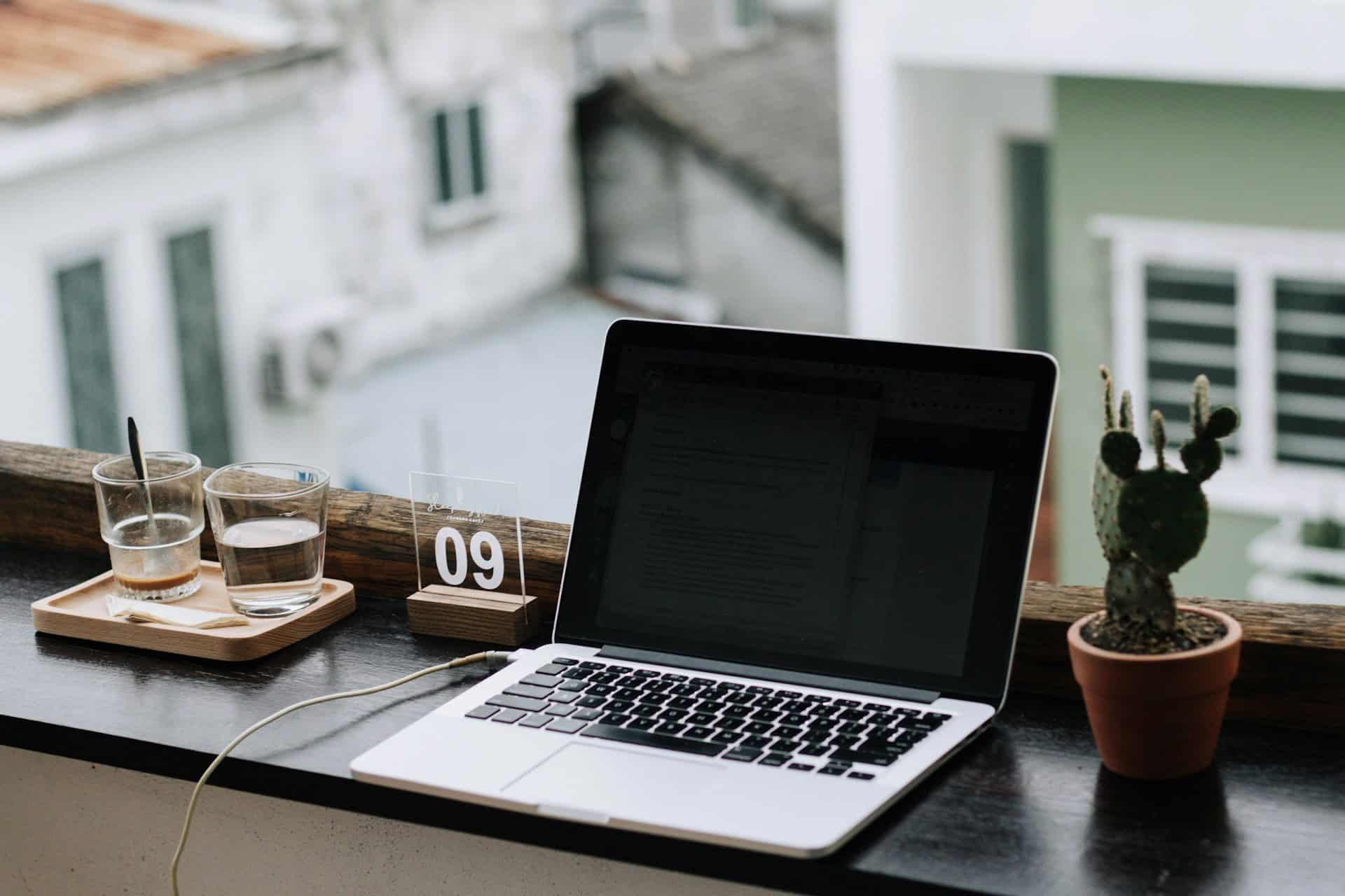 Laptop on a windowsill with coffee and city view for remote work while traveling.