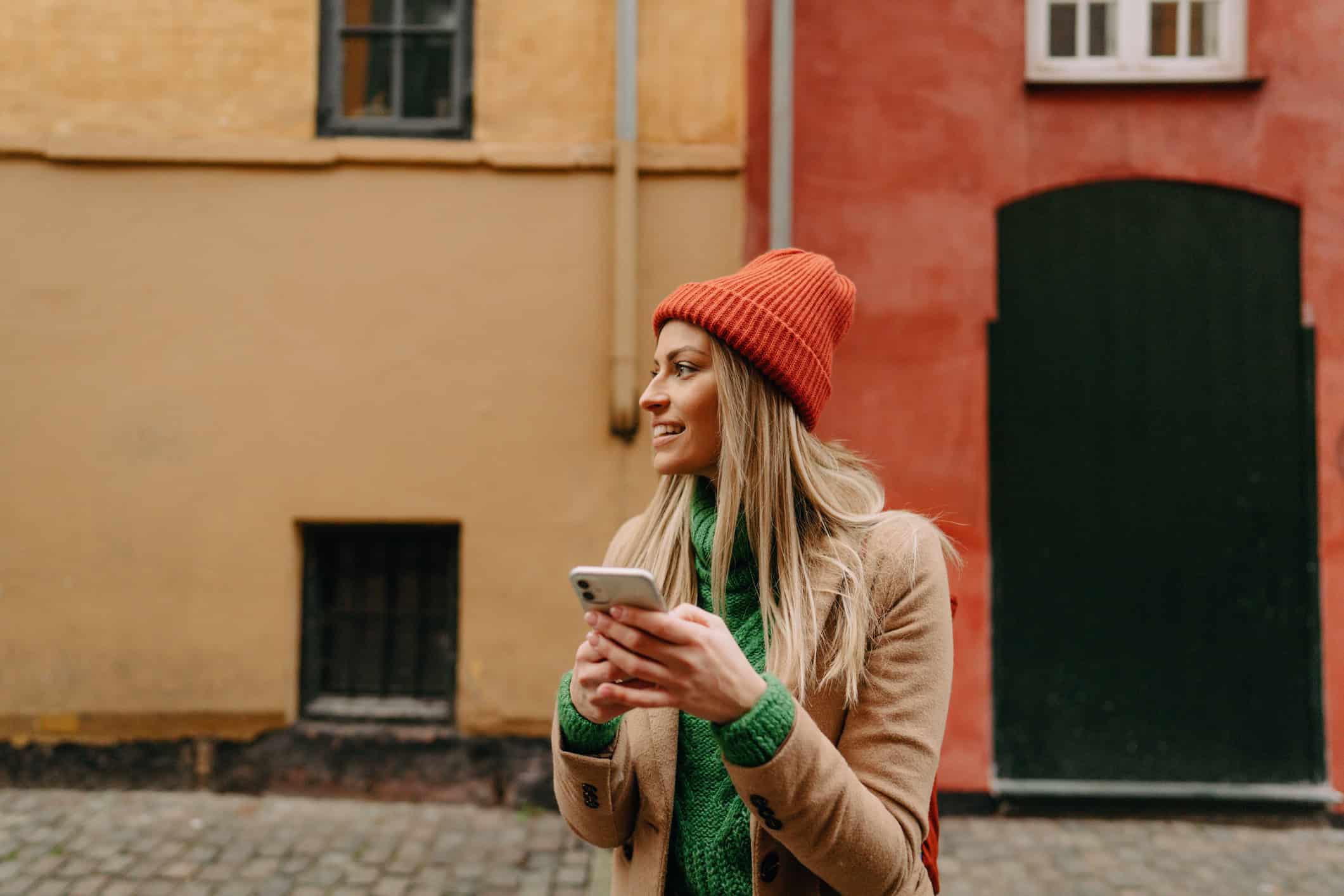 Traveler using a smartphone with Europe eSIM on a cobblestone street in Denmark