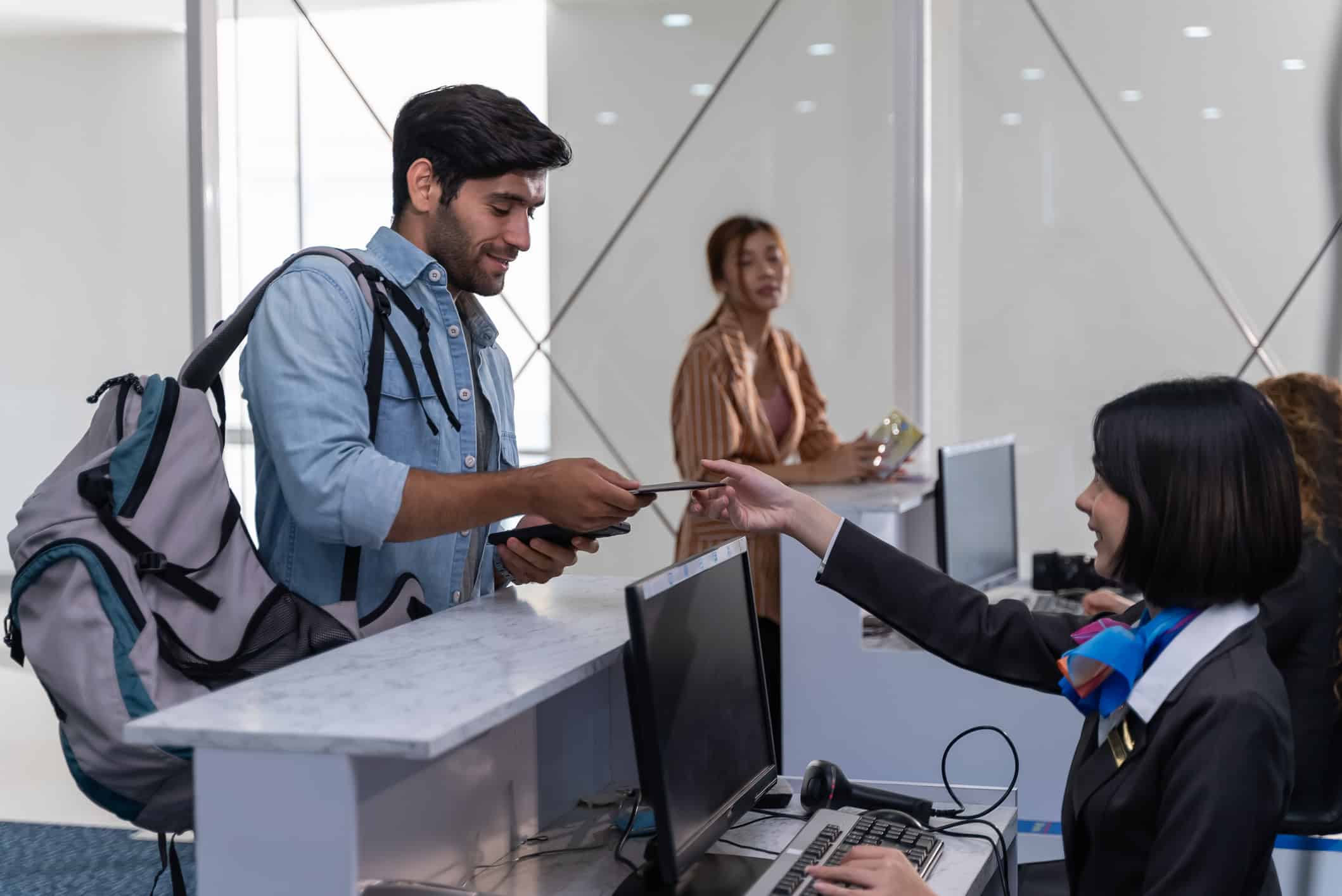 Traveler with backpack presenting passport at airport check-in counter for international travel