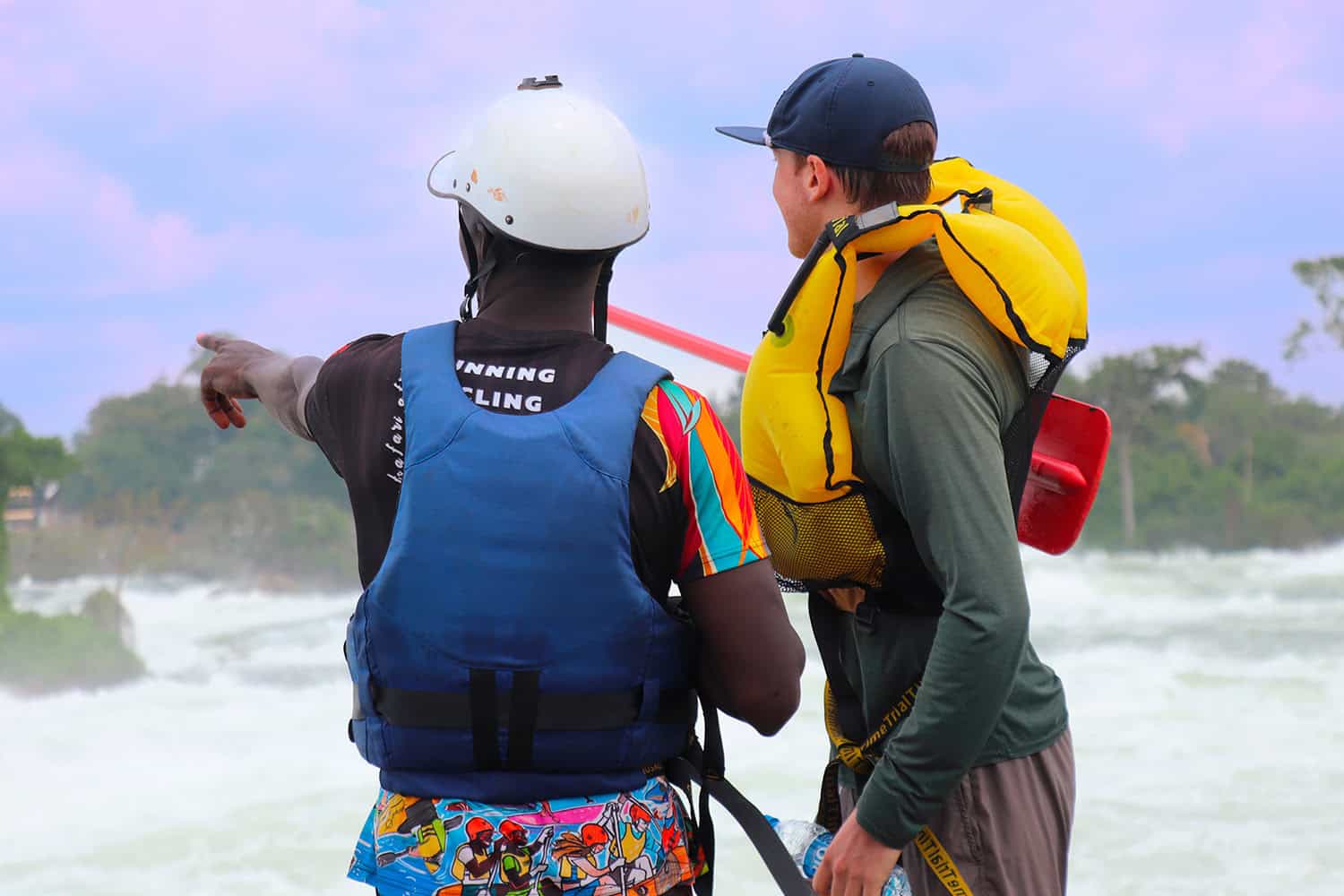 Rafting guide speaking with a traveler beside the Nile River in Uganda