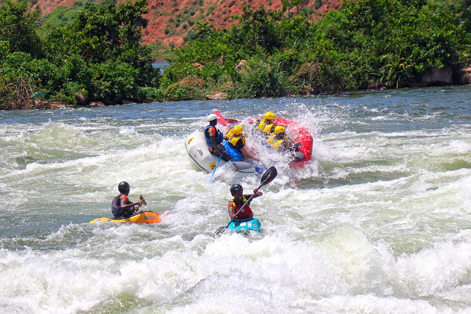 Safety kayakers assisting a rafting group in whitewater on the Nile River