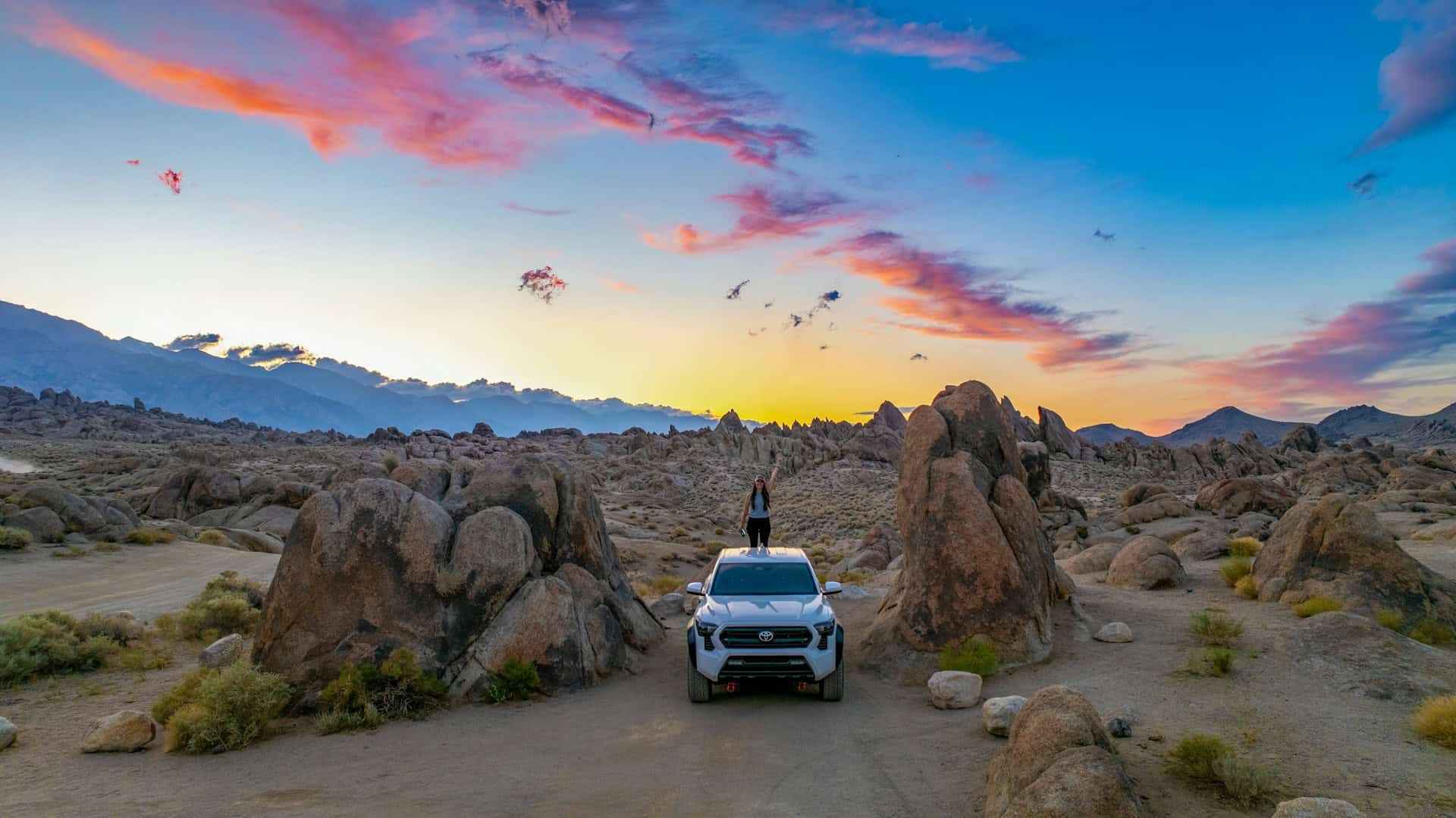 SUV parked in Alabama Hills, California, at sunset during a remote desert road trip