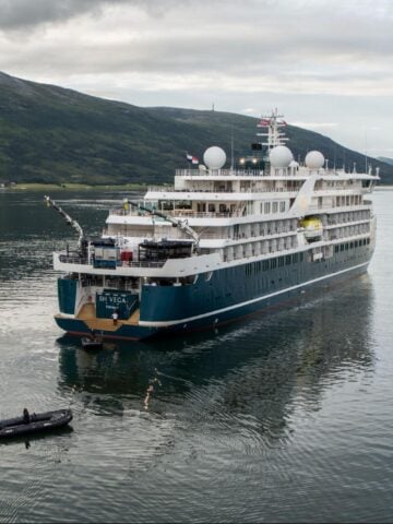 Swan Hellenic SH Vega expedition cruise ship sailing in Arctic waters near mountainous coastline