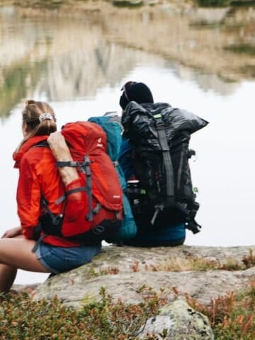 Two backpackers resting beside a lake in the Pyrénées National Park during a trekking trip