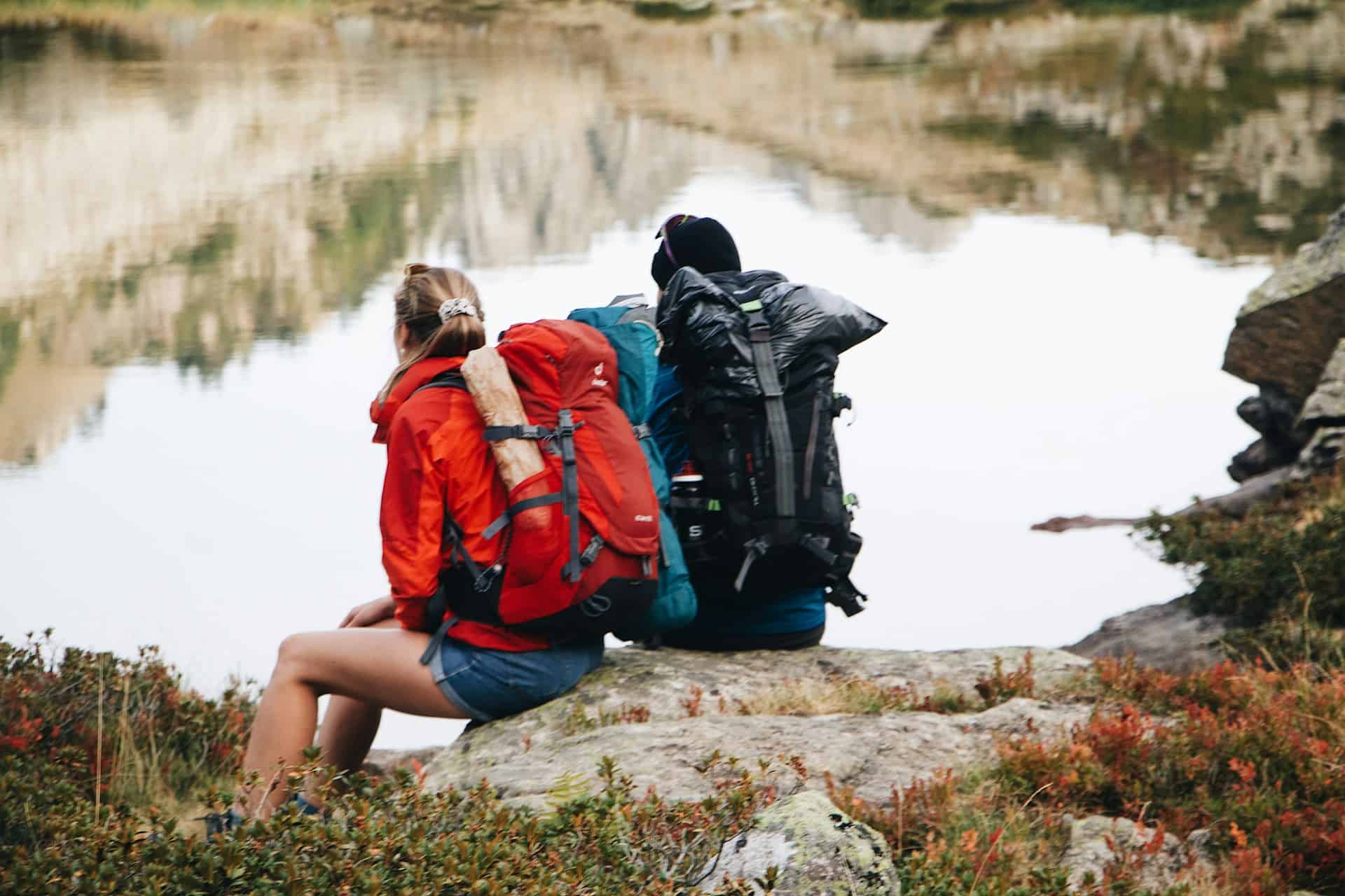 Two backpackers resting beside a lake in the Pyrénées National Park during a trekking trip