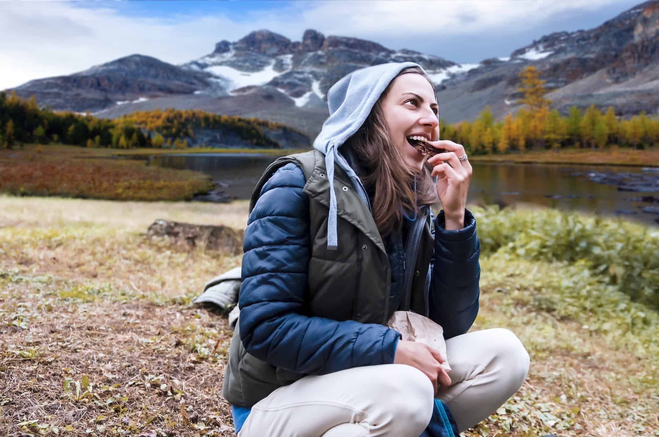 Hiker eating beef jerky during a backpacking trip in mountains