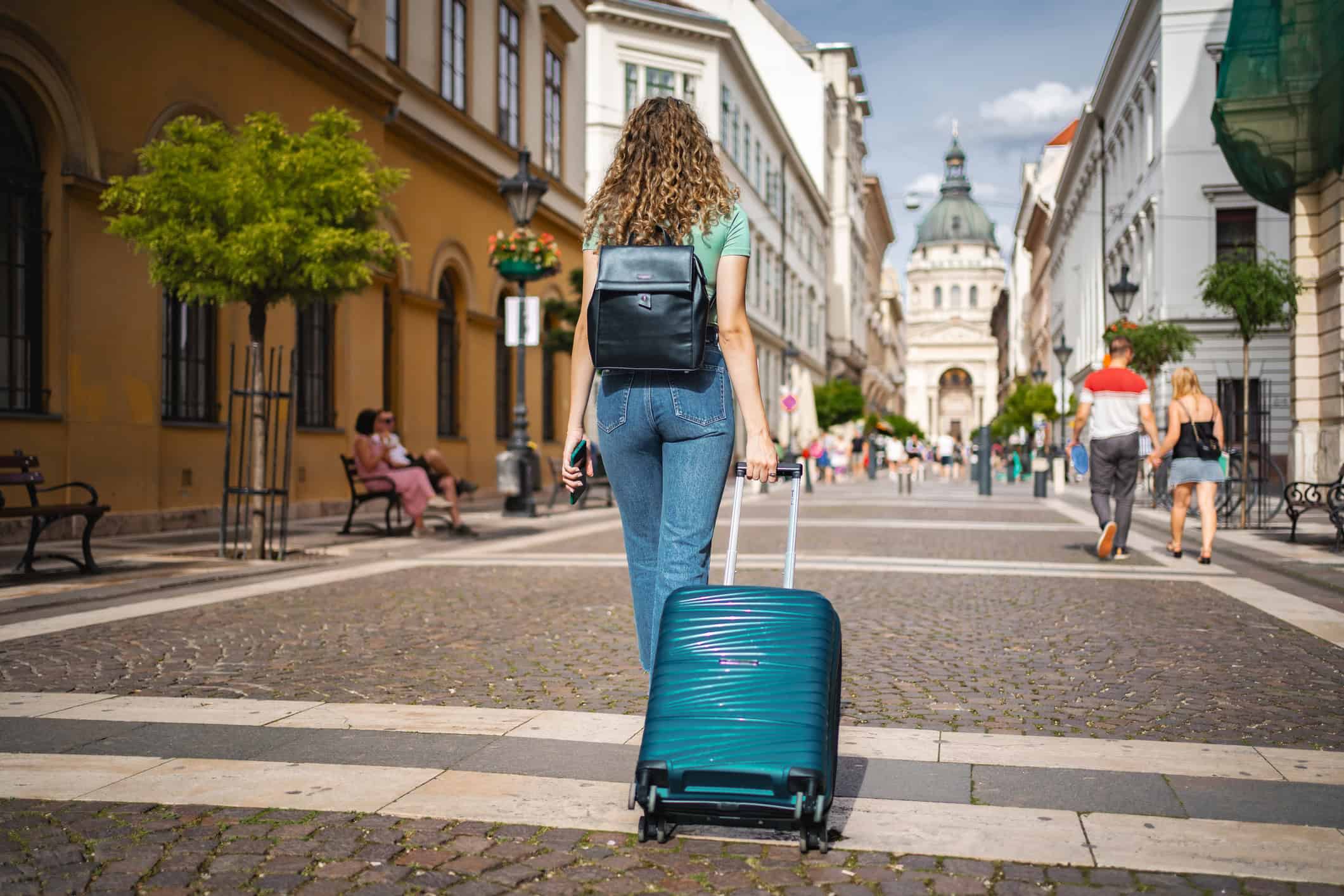 A traveler moving to Europe from the U.S. pulls a suitcase through a historic street in Budapest, Hungary.