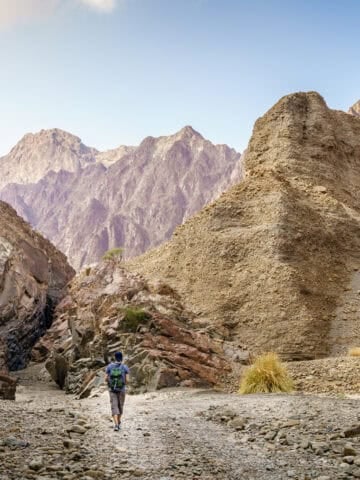 Independent traveler hiking through a wadi in the Hajar Mountains near Hatta, UAE