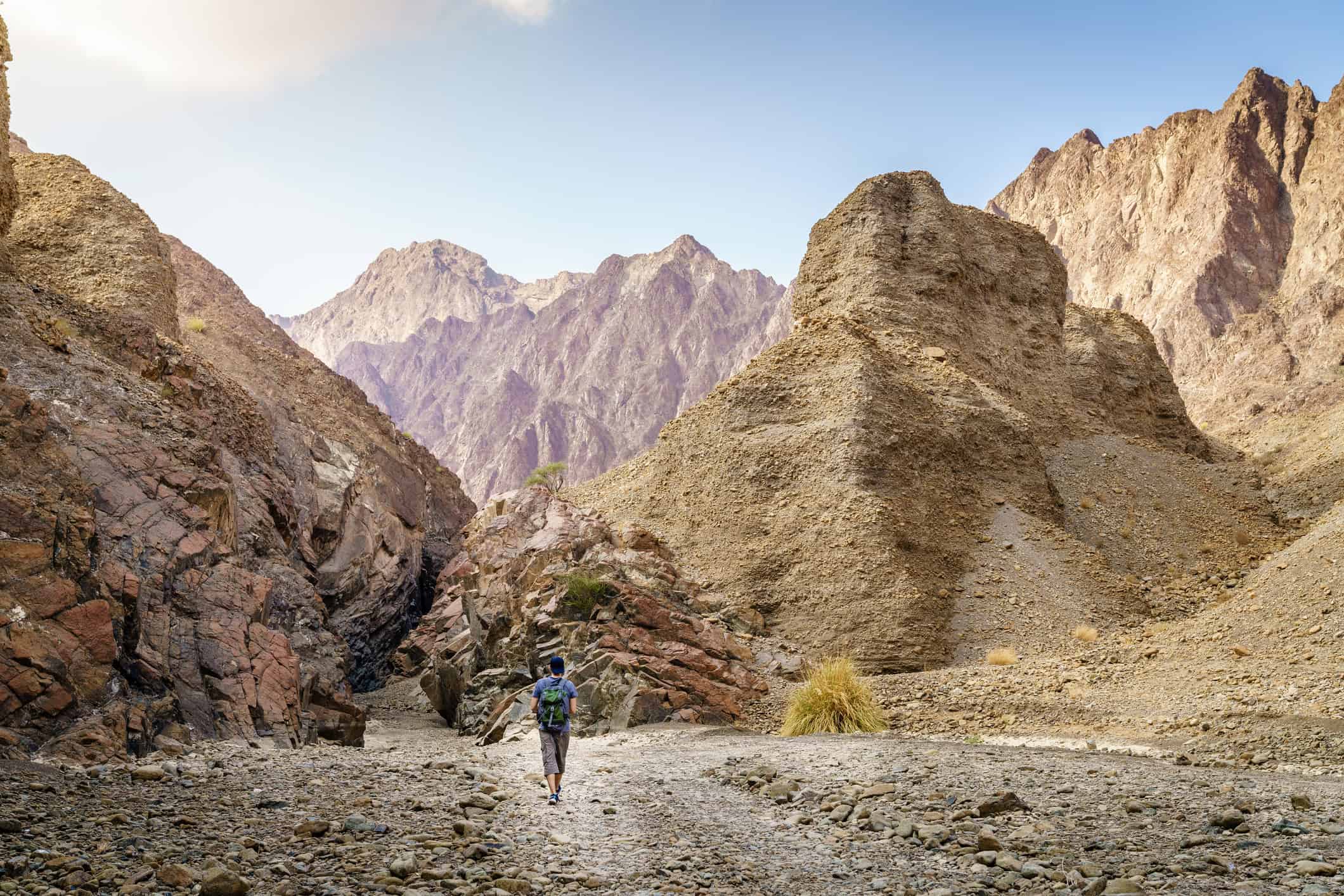 Independent traveler hiking through a wadi in the Hajar Mountains near Hatta, UAE