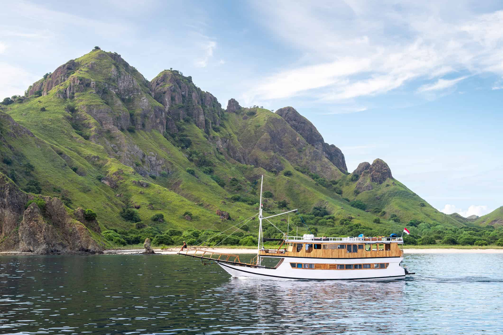 Boat sailing near lush green mountains in Komodo National Park.
