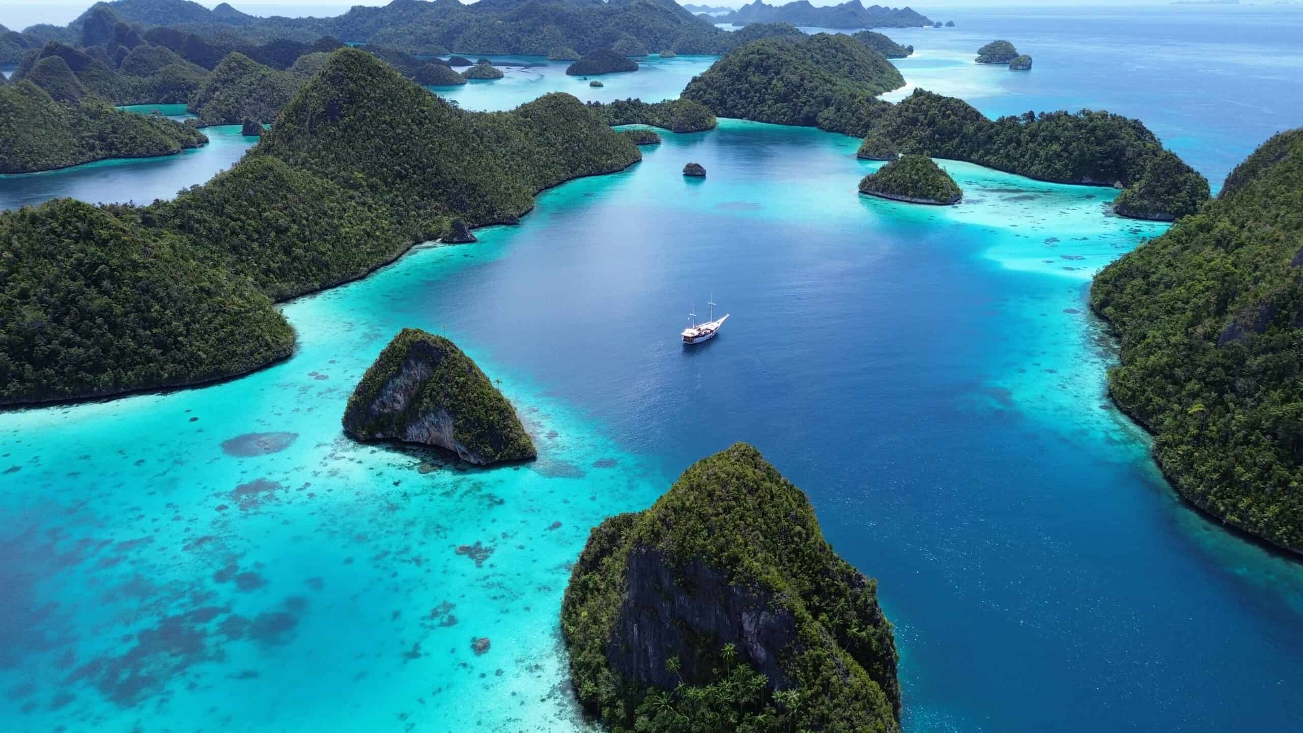 A liveaboard sailing through the limestone islands of Raja Ampat, Indonesia.