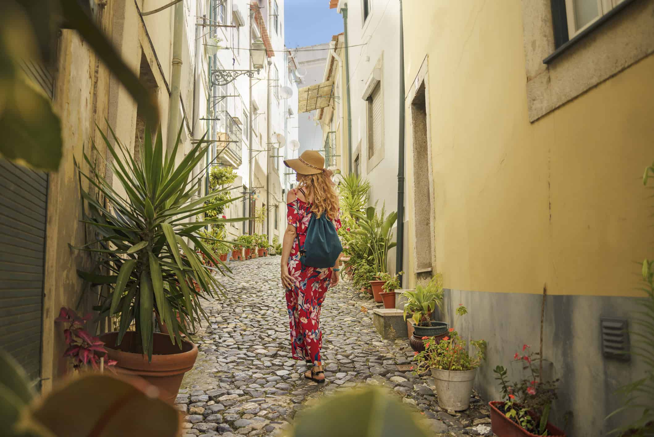 Traveler walking along a narrow cobblestone street while exploring a historic neighborhood.