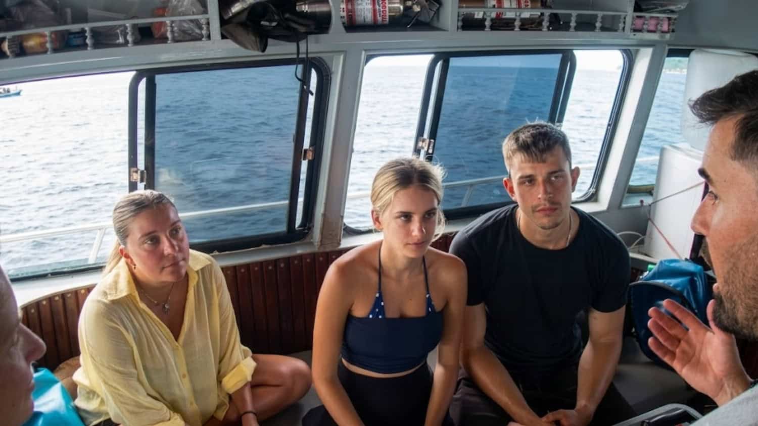 Three divers listening to an instructor aboard a boat in Thailand.