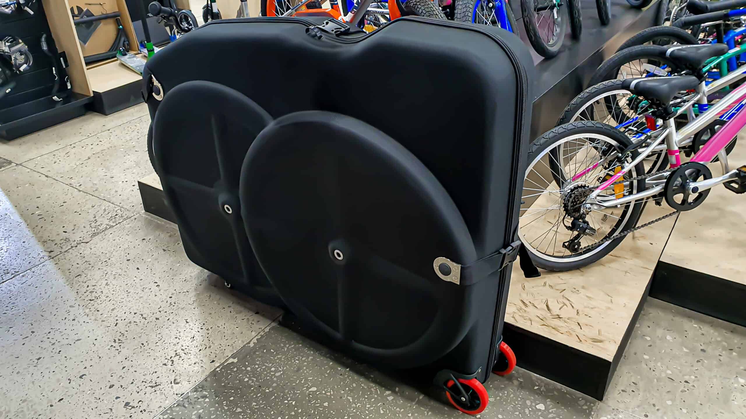 Hard-sided bicycle travel case with wheels in a bike shop