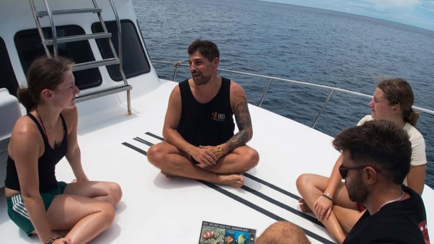 LB Diving instructor briefing three divers seated on the deck of a dive boat.